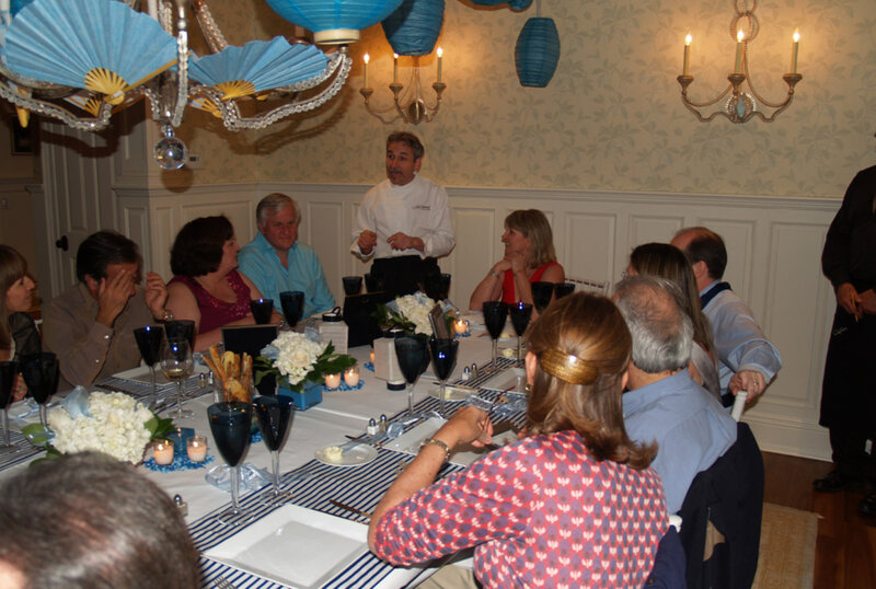 Chef Giorgio talking to party guests at table with blue table cloth and deocrations