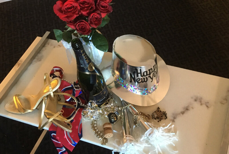 Champagne bottles, noise makers and party hats on marble serving tray