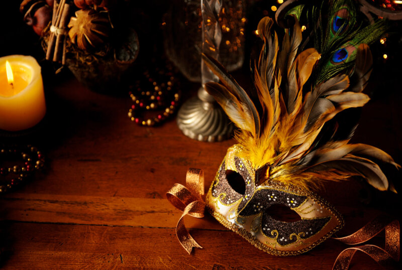 Wooden table with masquerade mask with candle and bead decorations