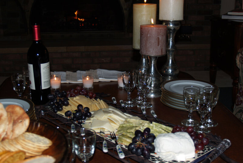 Platter with cheese, fruits and wine bottles with candle decorations