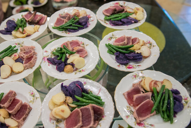 Many plates of filet mignon with vegetables and potatoes