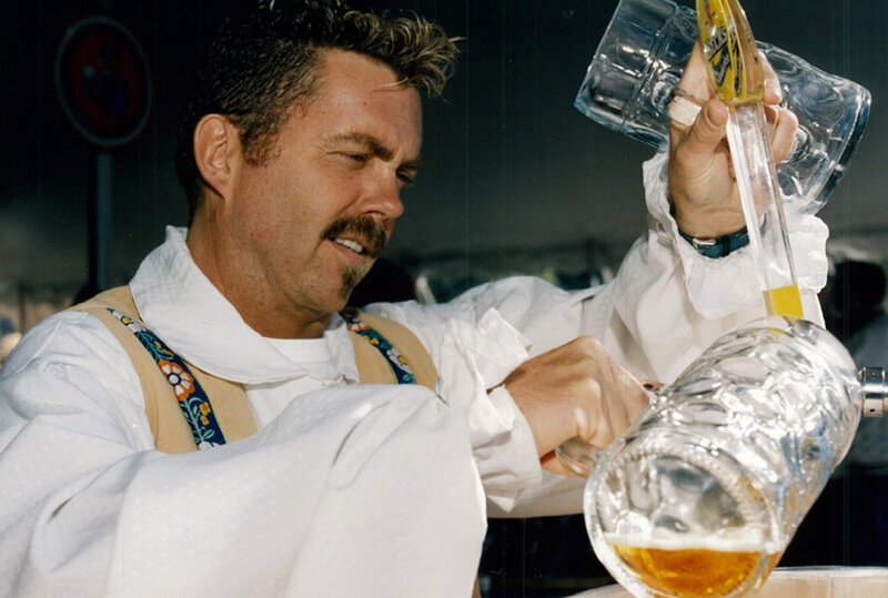Man in german lederhosen pour beer into large mug