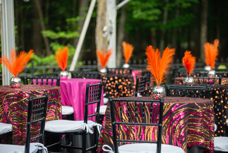 Tables deocrated with multicolored table cloths and feather center peices