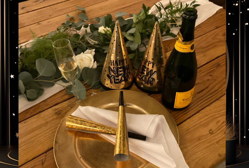 Champagne bottle and party hats on gold serving tray